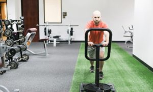 man pushing sled with weights in fitness center