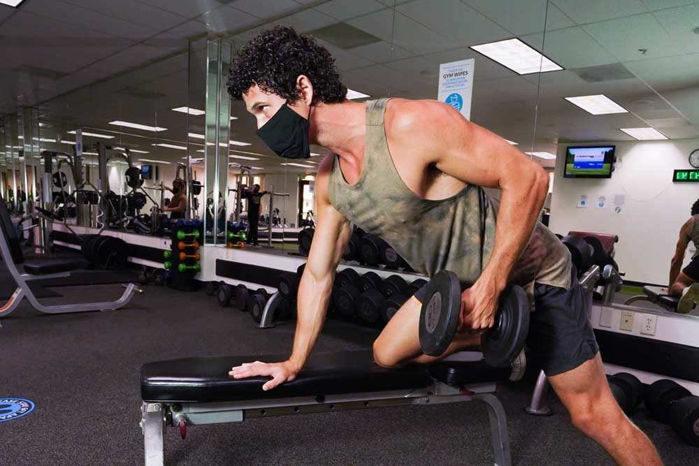 man with weights and face mask indoors
