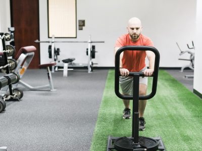 man pushing sled with weights in fitness center